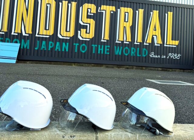 だいまつINDUSTRIALのロゴ前に並ぶヘルメット